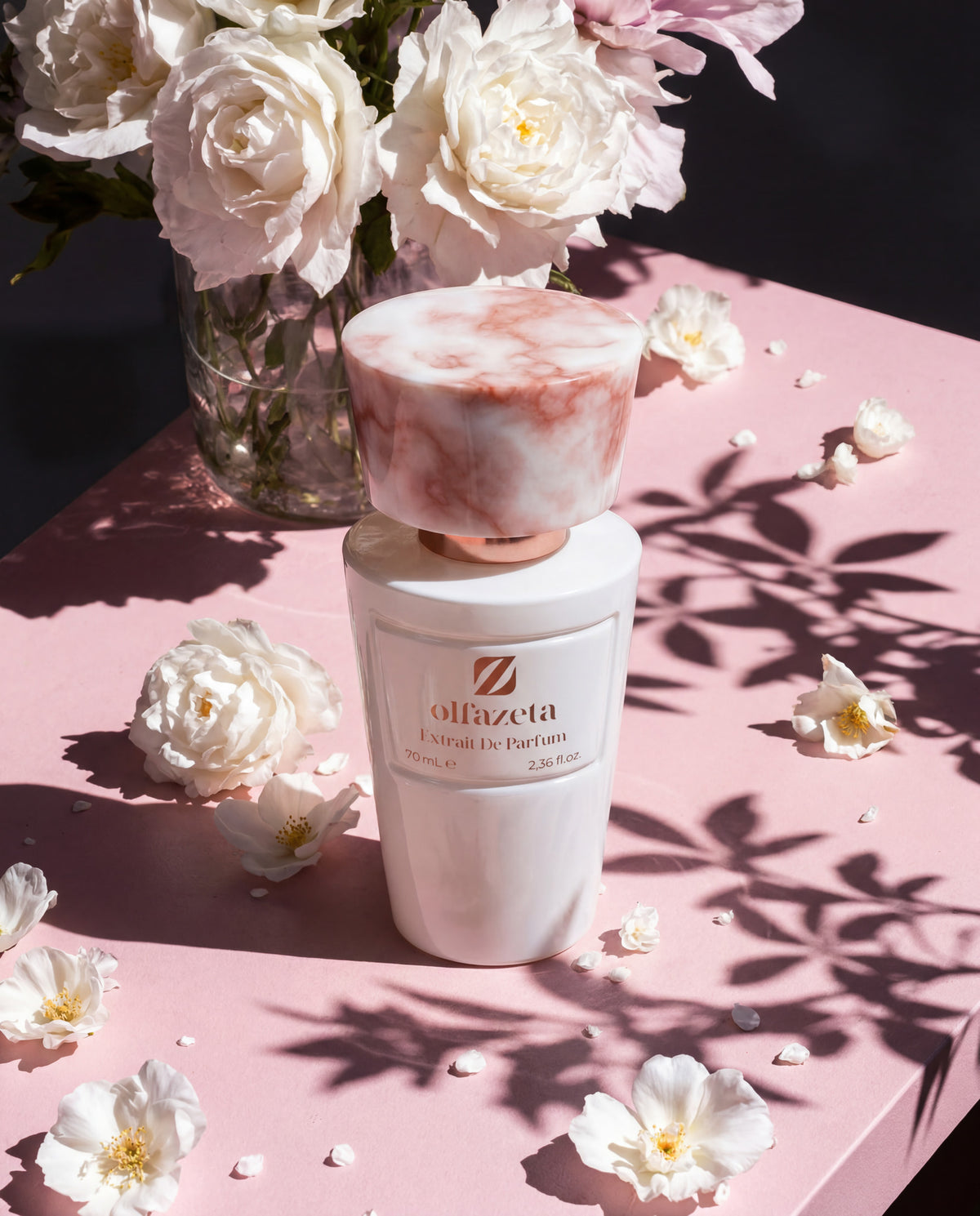 Frasco branco Olfazeta by Chogan Millésime N°51 rodeado de rosas brancas, sombras de folhagem ao sol